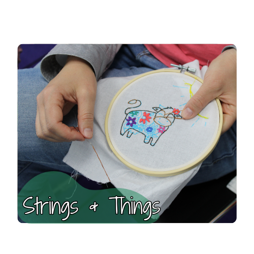 A woman embroidering a cow with flowers. Text reads: Strings and Things.