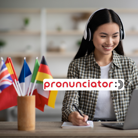 A young woman smiles in front of a computer and cup filled with multiple flags
